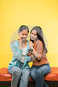 a girl cries sadly looking mobile phone while leaning on her friend& x27;s shoulder
