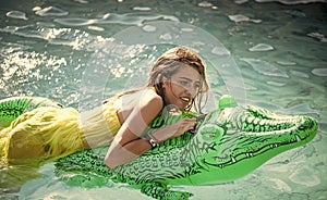 Girl on the crocodile. woman on sea with inflatable mattress. Relax in luxury swimming pool. Fashion crocodile