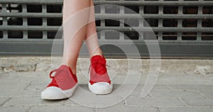Girl Cross her legs in red trainers