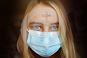 Girl with cross made from ash on forehead with face mask. Ash wednesday concept.