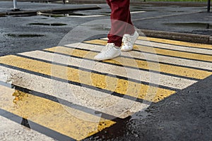 A girl crosses the road at a pedestrian crossing