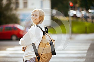 Girl crossing crosswalk and going to school outdoors in city