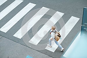 Girl crossing crosswalk and going to school outdoors in city