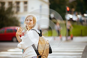 Girl crossing crosswalk, hand waving and going to school