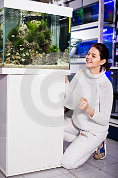 Girl crouched next to an aquarium with fish