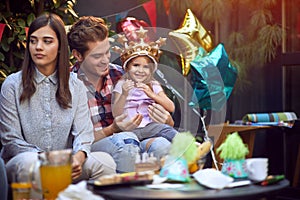 Girl with crown at head enjoying at birthday party with family