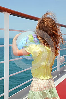 Girl on cruise liner deck and holding globe