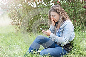 The girl is crying looking at her smart phone.