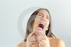 Girl crying while pressing a pimple on her chin photo