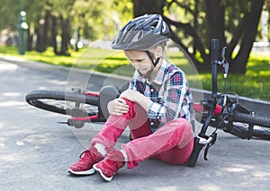 Crying girl is sitting next to her bike