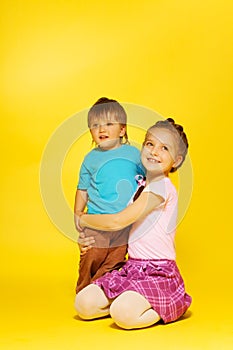 Girl cuddle standing child while sitting on floor