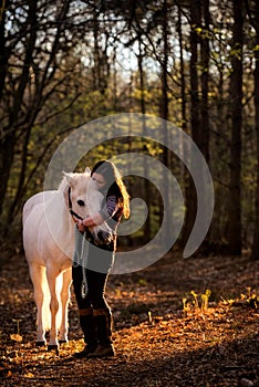 Girl Cuddling White Horse in Woods