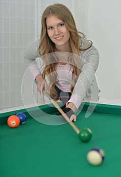 Girl with cue playing billiard