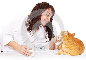 Girl with a cup of coffee and her cat in bed