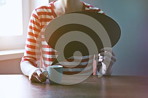 Girl with cup of coffee holding blank plate as bubble