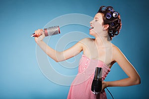 Girl with curlers in hair holds hairdreyer