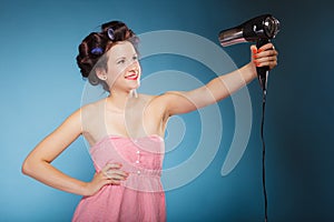 Girl with curlers in hair holds hairdreyer
