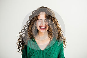 Girl with curly hair at hairdresser at white wall. Parisian girl in winter clothes. Fashion look and beauty concept