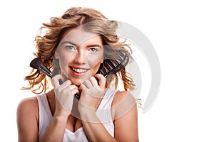 Girl with curly hair holding makeup brush and comb.