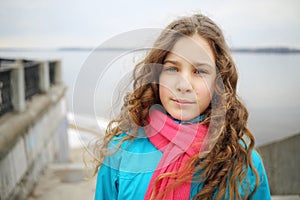 Girl with curly hair poses on river embankment at