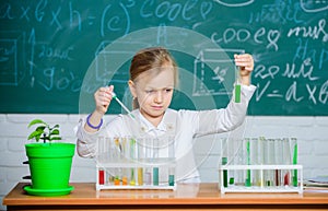 Girl cute school pupil play with test tubes and colorful liquids. School chemical experiment. School education