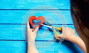 girl cuts the heart with scissors, the concept of breaking relations, quarrels and divorce. Betrayal of the othere. blue back