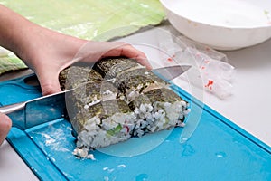 The girl cuts the ready-made sushi in half with a sharp kitchen knife