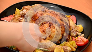 Girl cuts Roasted chicken or grilled turkey for Christmas or Thanksgiving in sauce with potatoes vegetables and rosemary