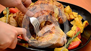 Girl cuts Roasted chicken or grilled turkey for Christmas or Thanksgiving in sauce with potatoes vegetables and rosemary