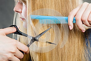 Girl is cutting her hair down.