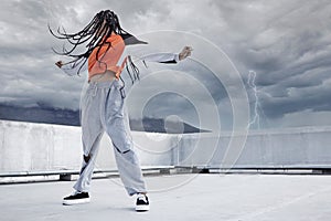 Girl, dance and hip hop outdoor on city rooftop with lightning storm and cool gen z streetwear fashion. Woman, moving