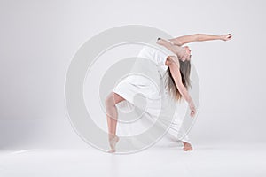 Girl in a dance pose in a white dress.