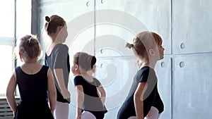 Girl dancer in ballet school learns to dance. Little Ballerina in training in black dancing suit. Children`s ballet