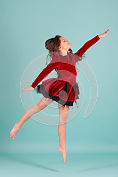 Girl dancer in red dress dance barefoot on blue background