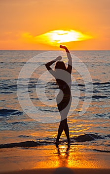 The girl dances at sunset on the seashore