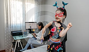 Girl dancing in disguise while her mother teleworking