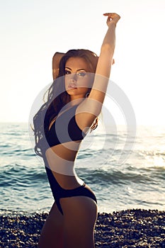 girl with dark hair in swimsuit posing on beach