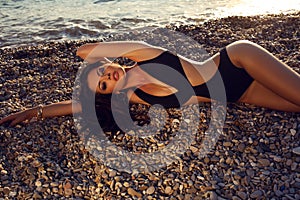 girl with dark hair in swimsuit posing on beach