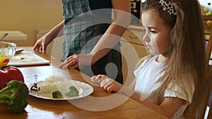 The girl decisively pushes away a plate of food. Looks at the mother and shakes his head, the child refuses to eat