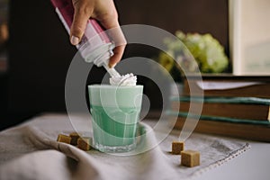 Girl is decorate cream in cup of green mint coffee. Milk shake, cocktaill, frappuccino.