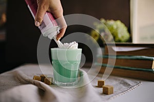 Girl is decorate cream in cup of green mint coffee. Milk shake, cocktaill, frappuccino.