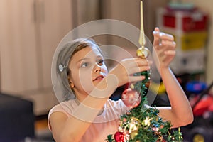 The girl decorates the Christmas tree. Children in Xmas