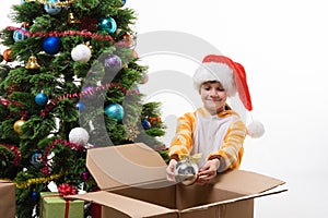 A girl decorates a Christmas tree and takes out Christmas toys from a box