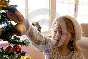 Girl decorating tree at Christmas time