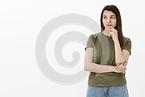 Girl deep thinking spacing out as looking with interest, thoughtful at left side of copy space touching lip with finger