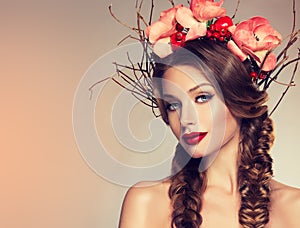 Girl with delicate wreath from flowers, fruits and twigs on her head.
