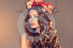 Girl with delicate wreath from flowers, fruits and twigs on her head.