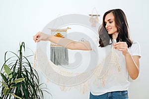 Girl demonstrates macrame, what she managed to make of a white rope