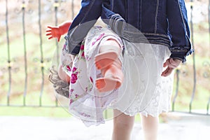 Girl with denim coat and spring dress stepping out with doll