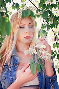 Girl in a denim jacket enjoys the flowers early in the morning